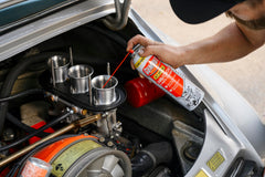 Gumout spray con tubo aplicador alcanzando garganta del carburador