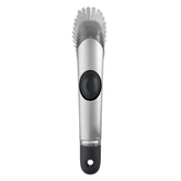 OXO cepillo frontal con mango mostrando diseño ergonómico y dosificación de jabón