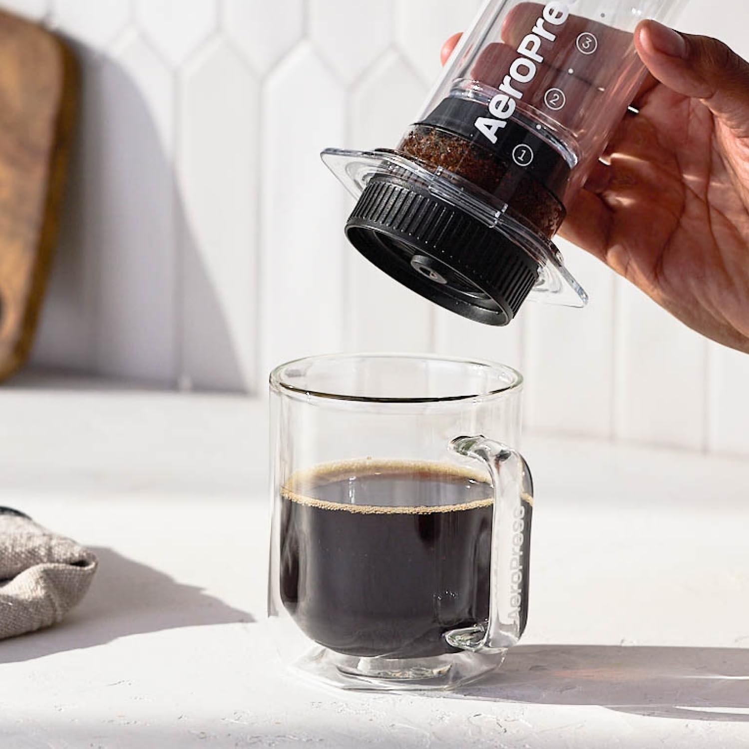 AeroPress tapa Flow Control junto a taza para comparar escala y mostrar portabilidad