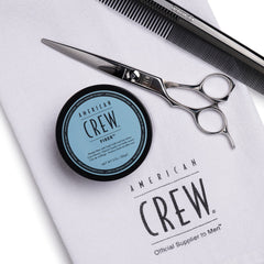 American Crew producto en uso mientras un hombre texturiza su corte corto