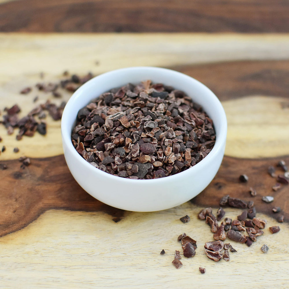 Mano comparando tamaño de Anthony's cacao nibs para visualizar porción y uso práctico