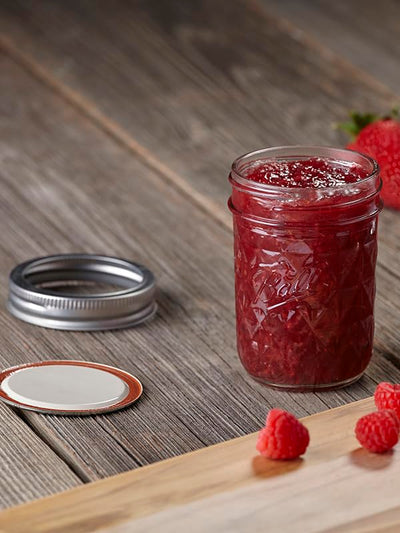 Ball lids on jars inside a water bath canner illustrating safe processing