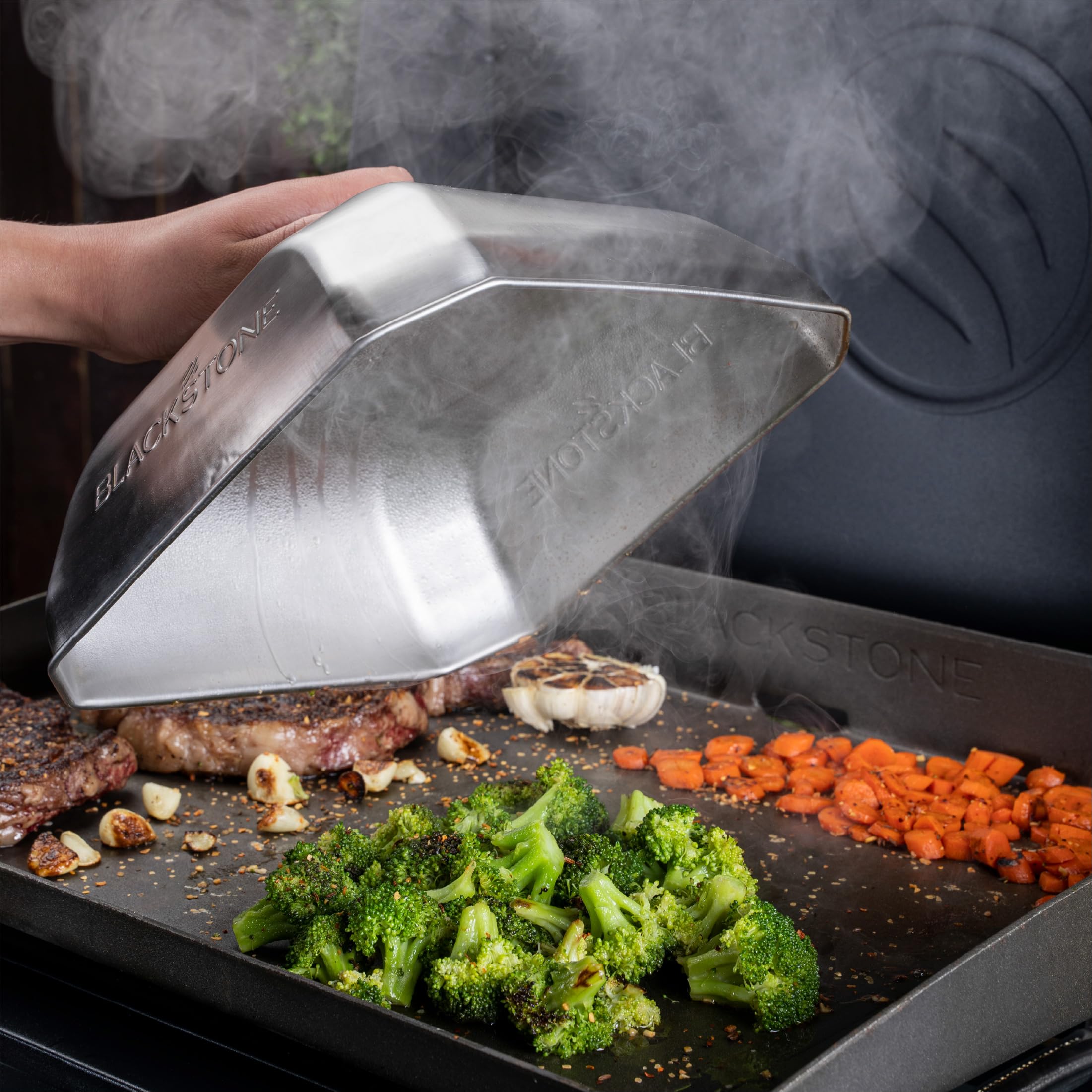 Blackstone tapa en uso sobre plancha con verduras vaporidas uniformemente