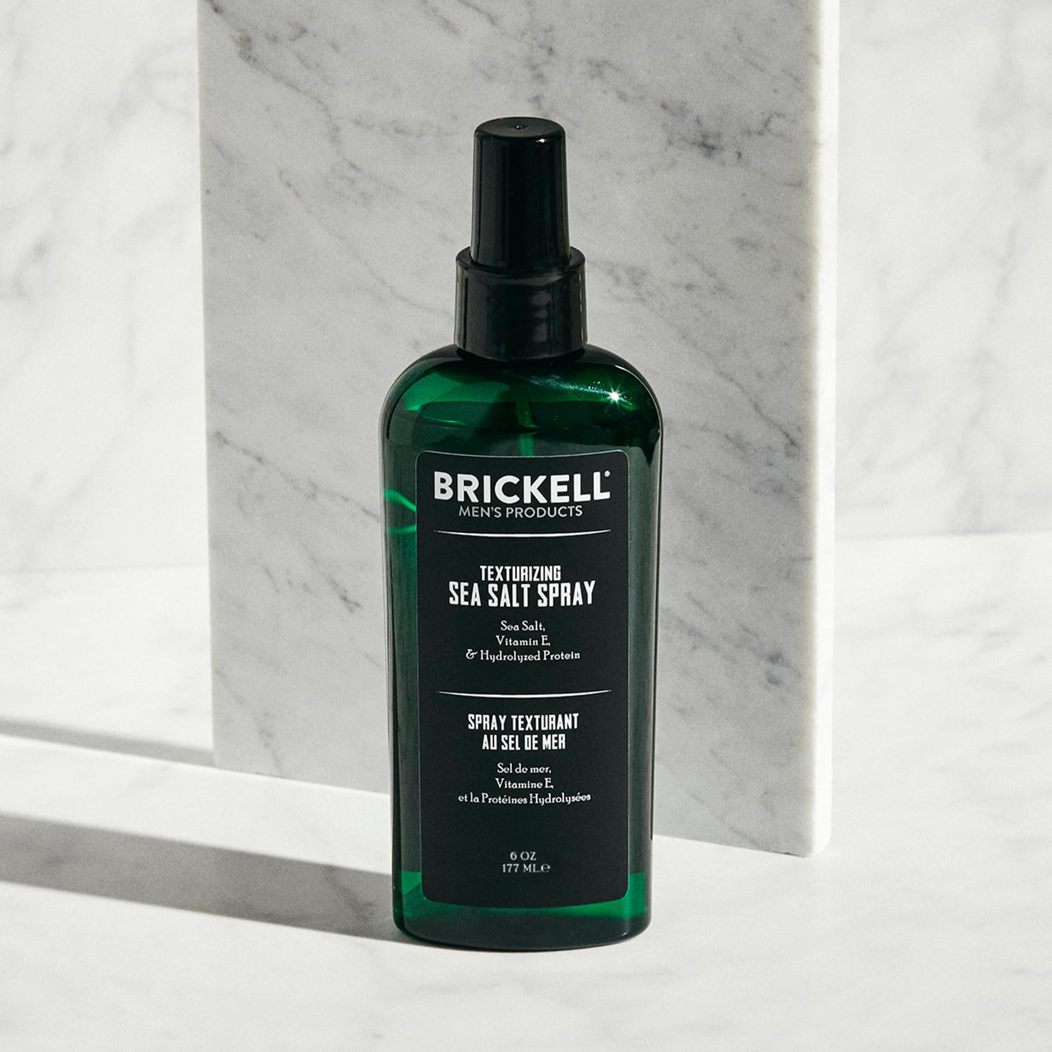 Brickell spray en mano durante la aplicación para crear volumen natural