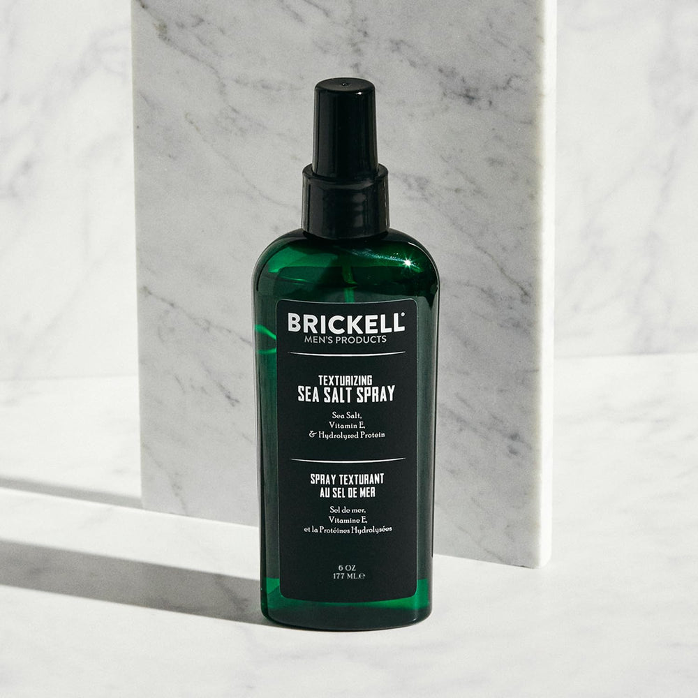 Brickell spray en mano durante la aplicación para crear volumen natural