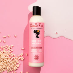 Camille Rose producto en mano aplicándose para desenredar y proteger cabello