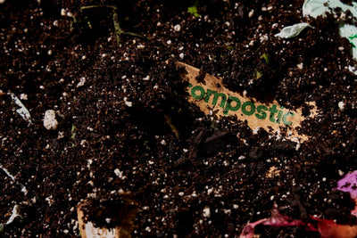 Compostic bag being added to a backyard compost pile showing home compostability