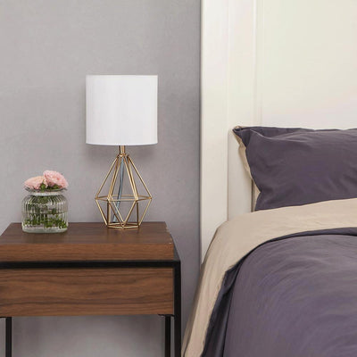 COTULIN gold lamp lit on a bedside table creating cozy ambient lighting