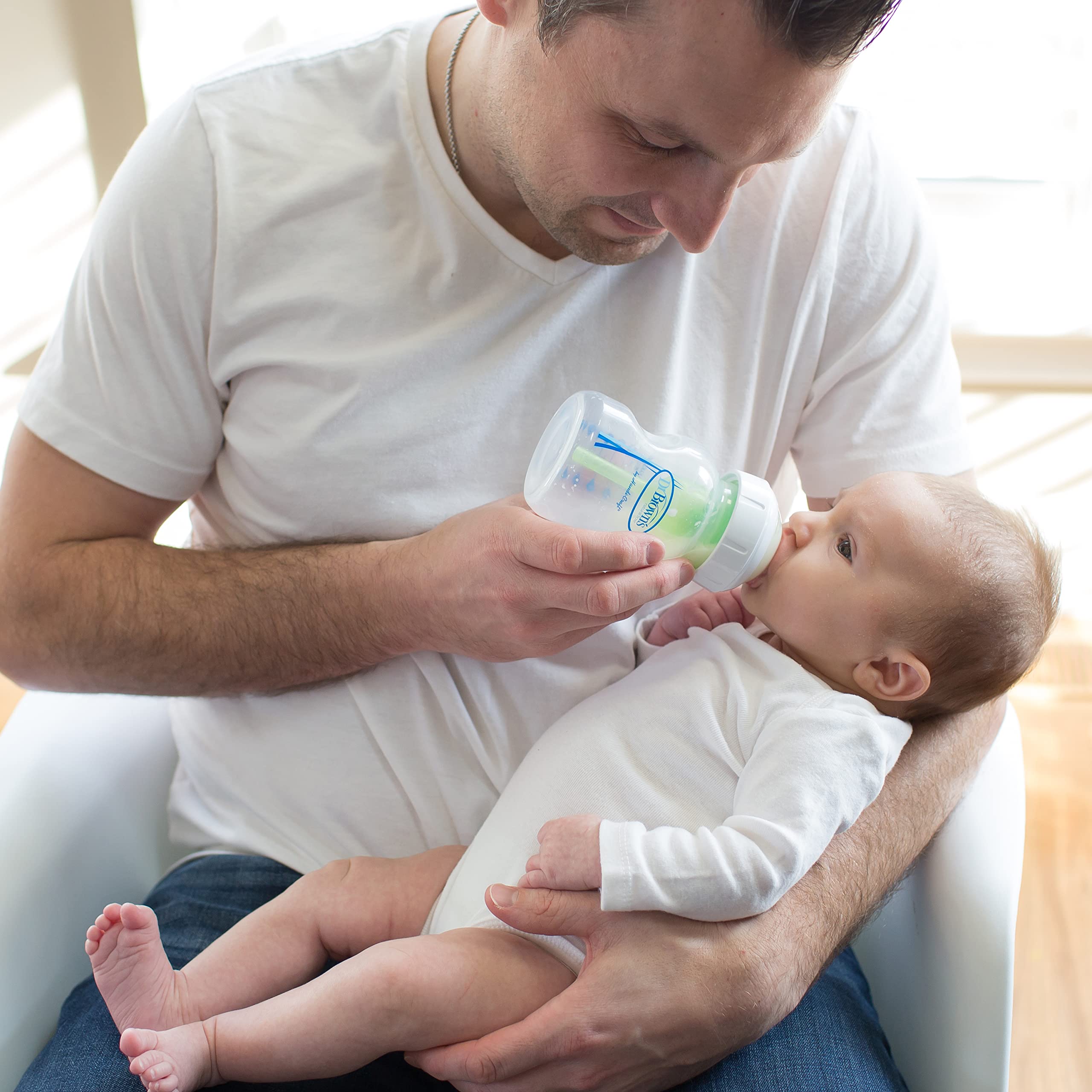 Dr. Brown's bottle in a caregiver's arms feeding a calm newborn