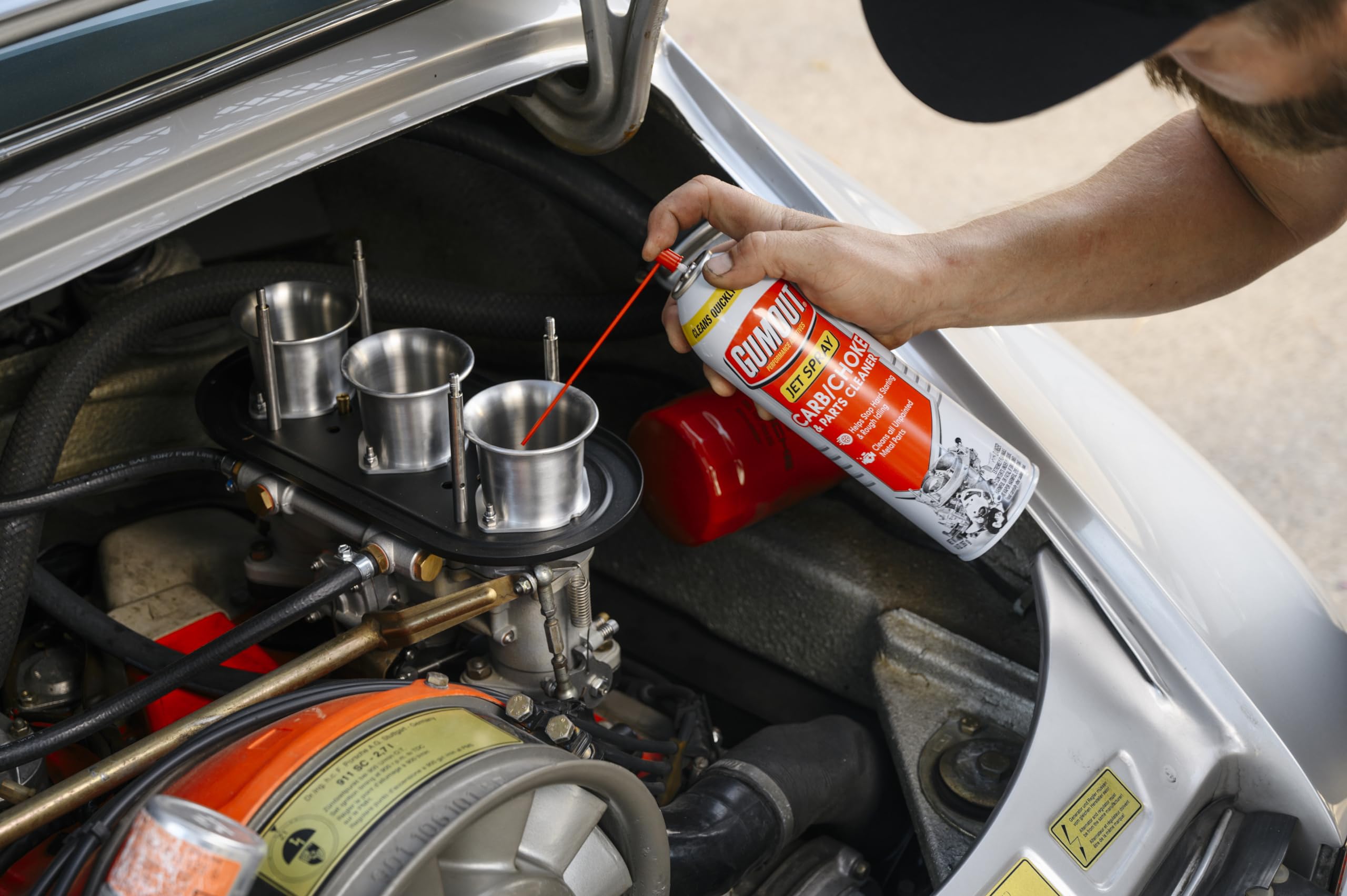 Gumout spray con tubo aplicador alcanzando garganta del carburador