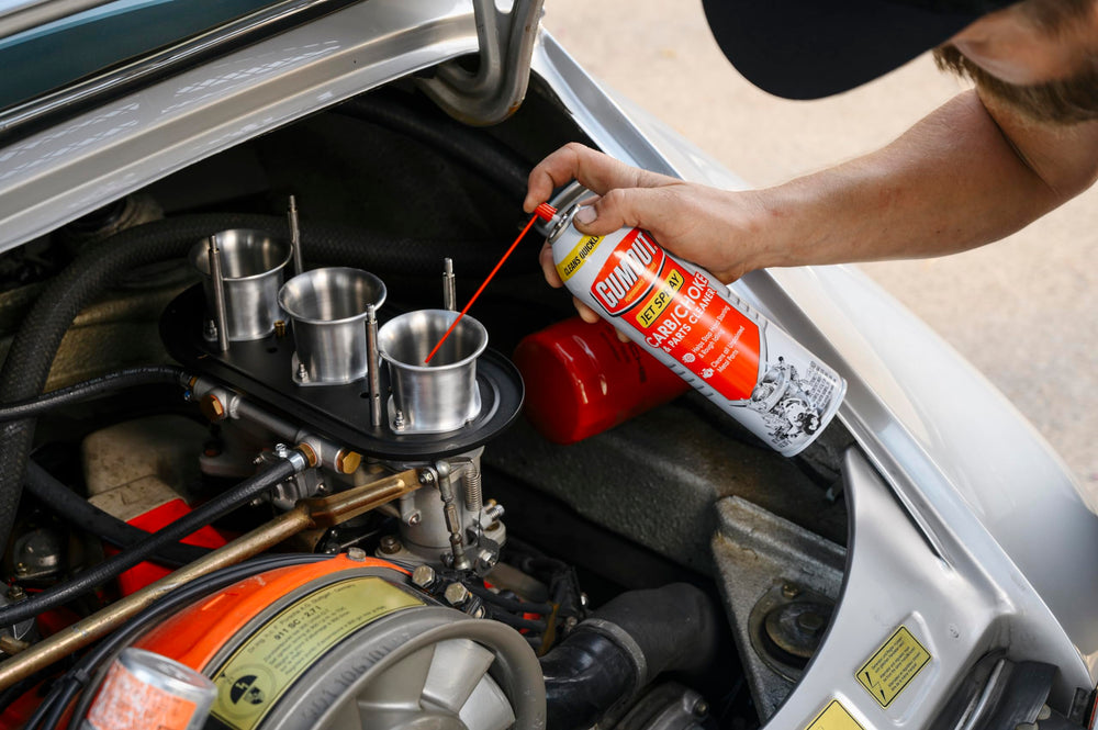Gumout spray con tubo aplicador alcanzando garganta del carburador