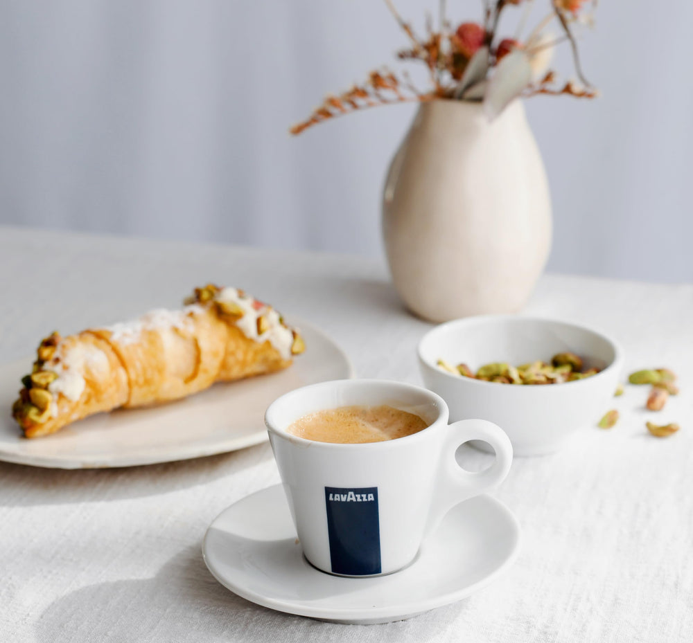 Lavazza Dek Filtro en mesa de desayuno con croissants, sugiere consumo relajado sin cafeína