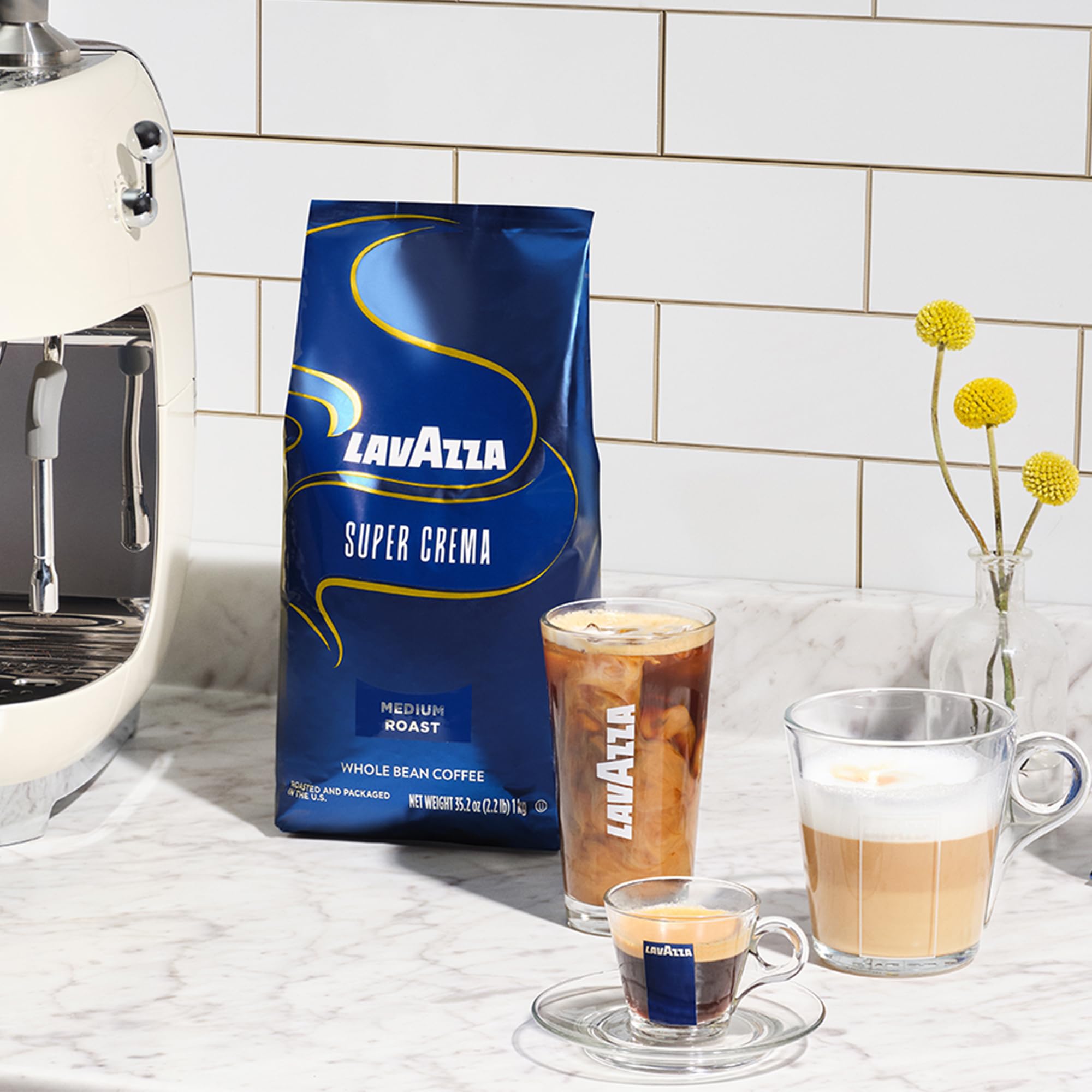 Whole beans beside a grinder and sealed Lavazza Super Crema bag demonstrating storage