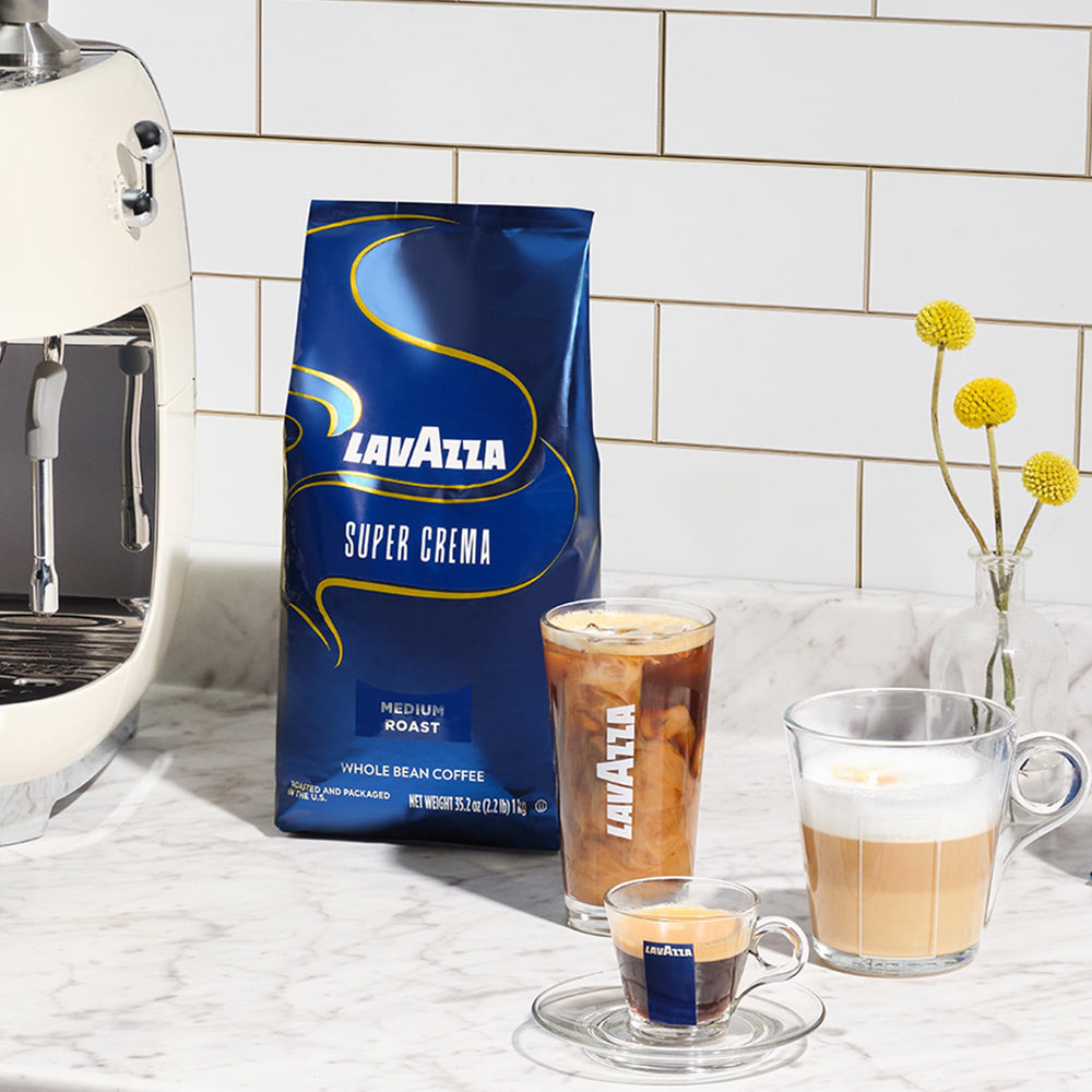 Whole beans beside a grinder and sealed Lavazza Super Crema bag demonstrating storage