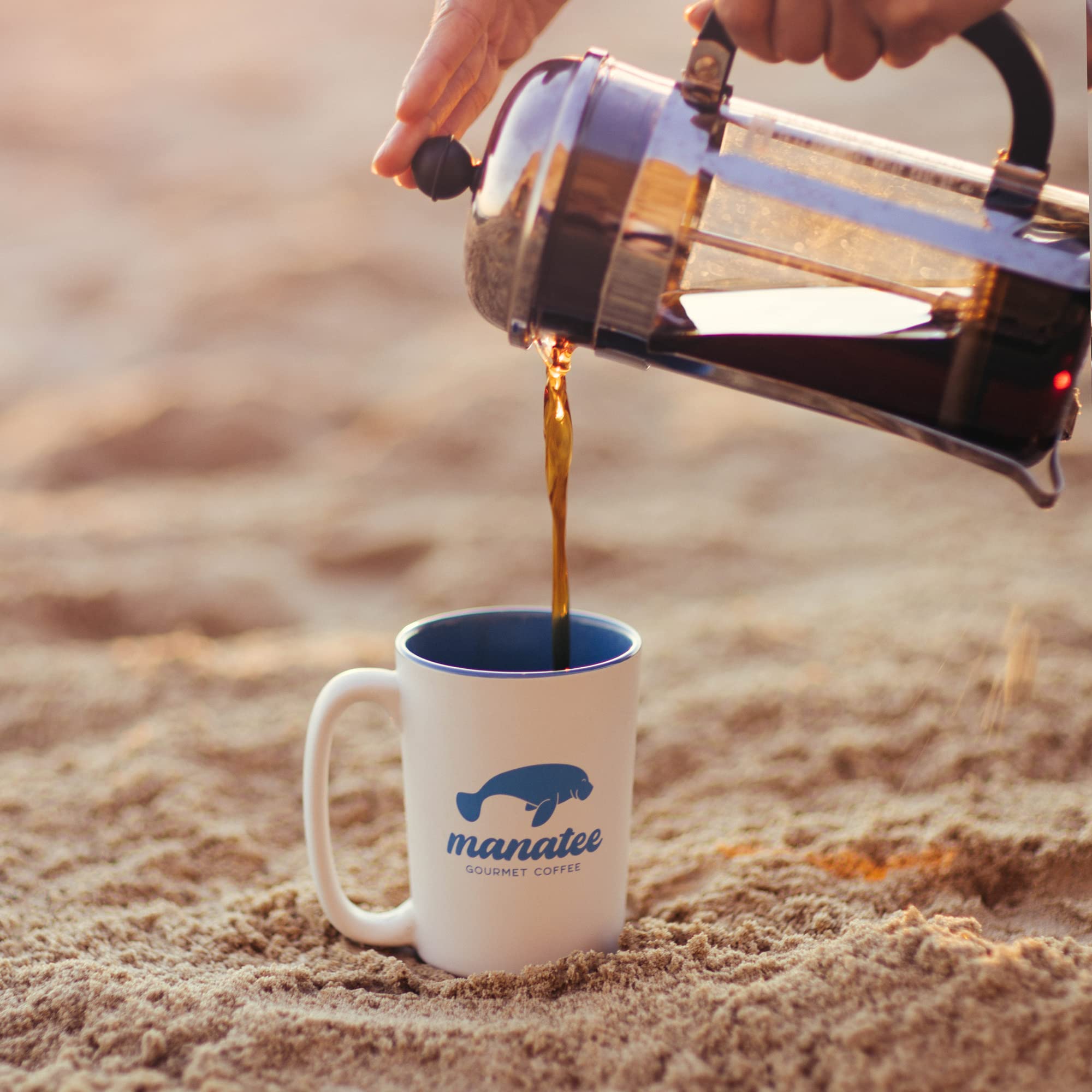 freshly brewed coffee being poured from carafe into cup with Manatee Gourmet beans visible benefit: showcases rich crema and inviting cup