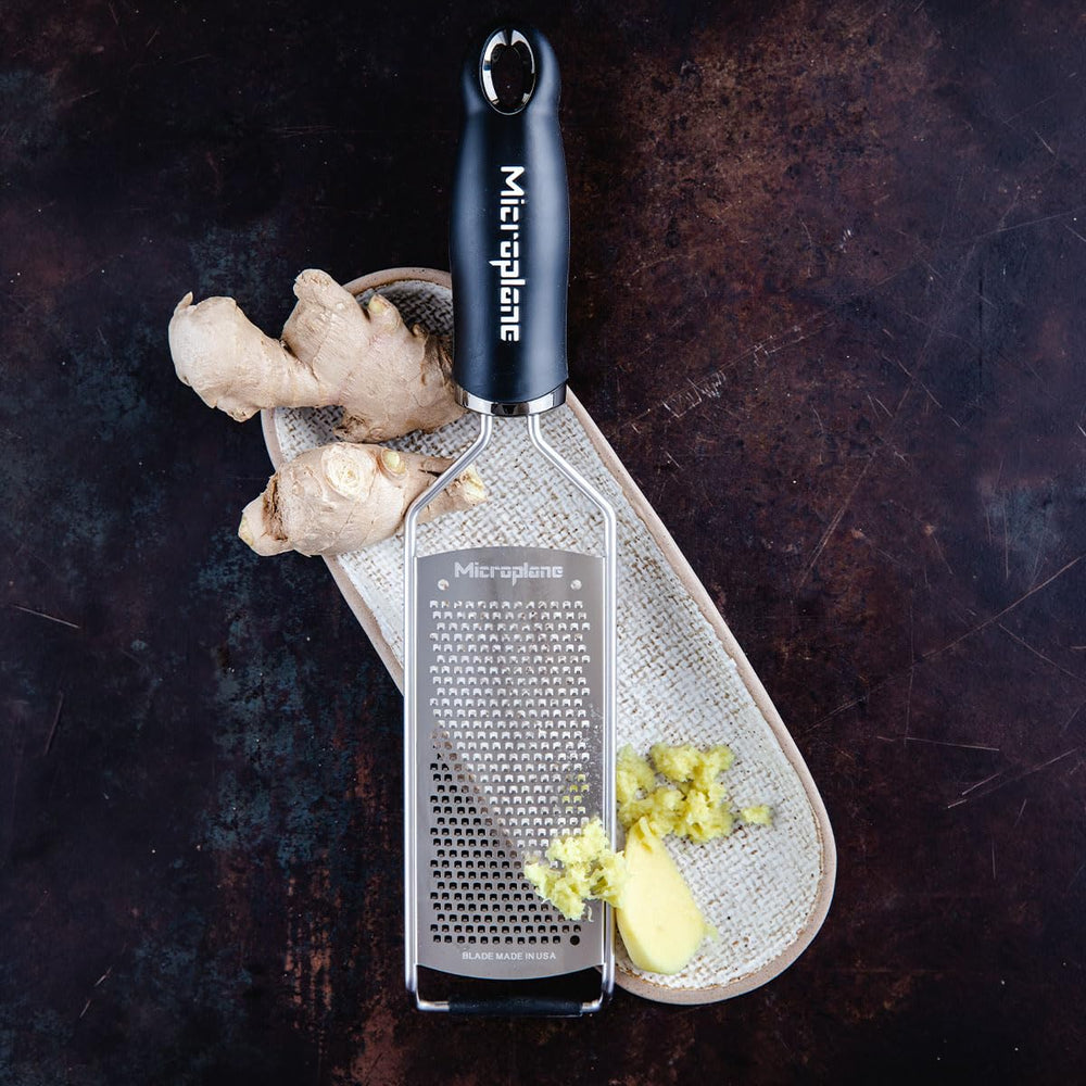 Microplane grater in use over pasta demonstrating even melting and easy finishing