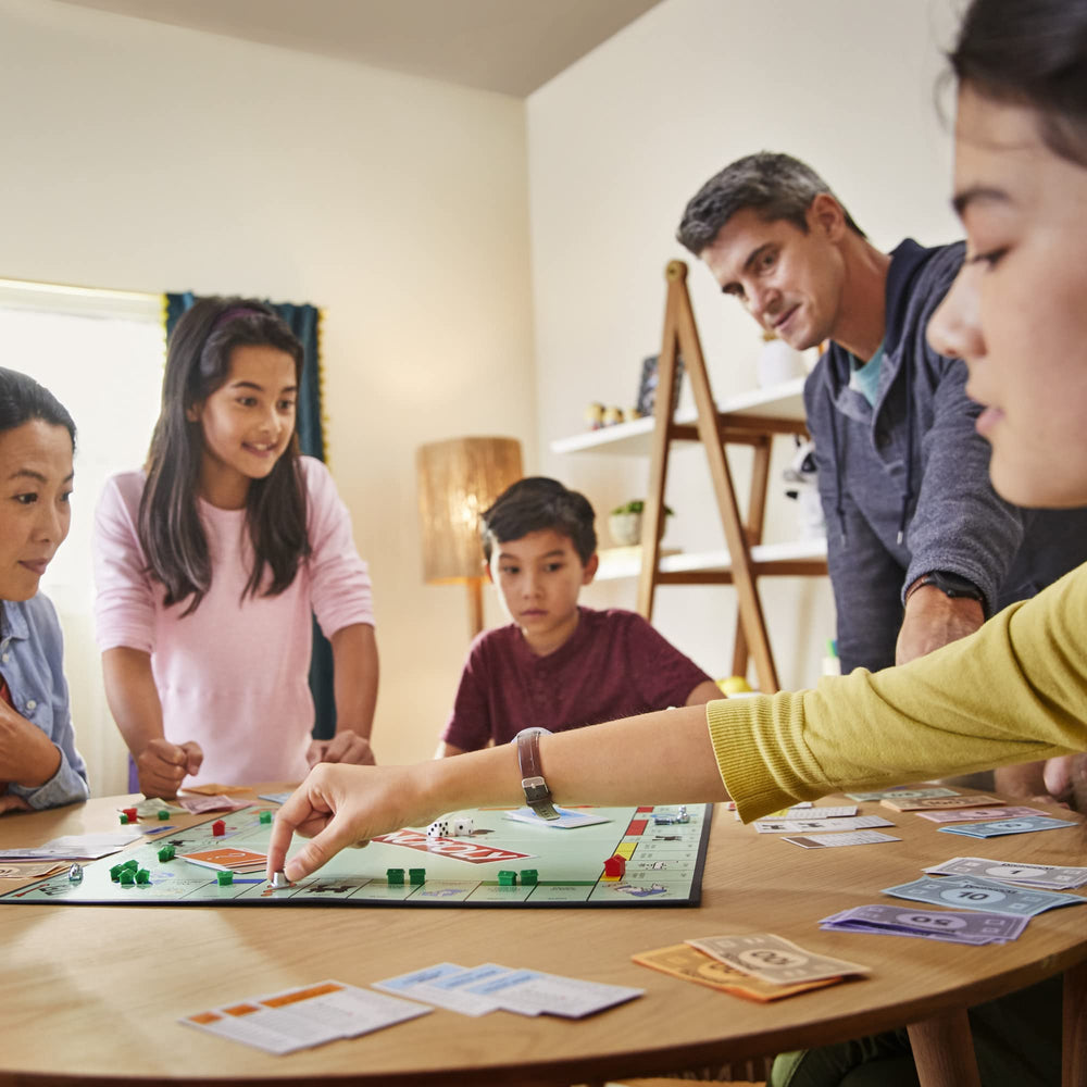 Monopoly jugadores en familia disfrutando partida, fomenta interacción social