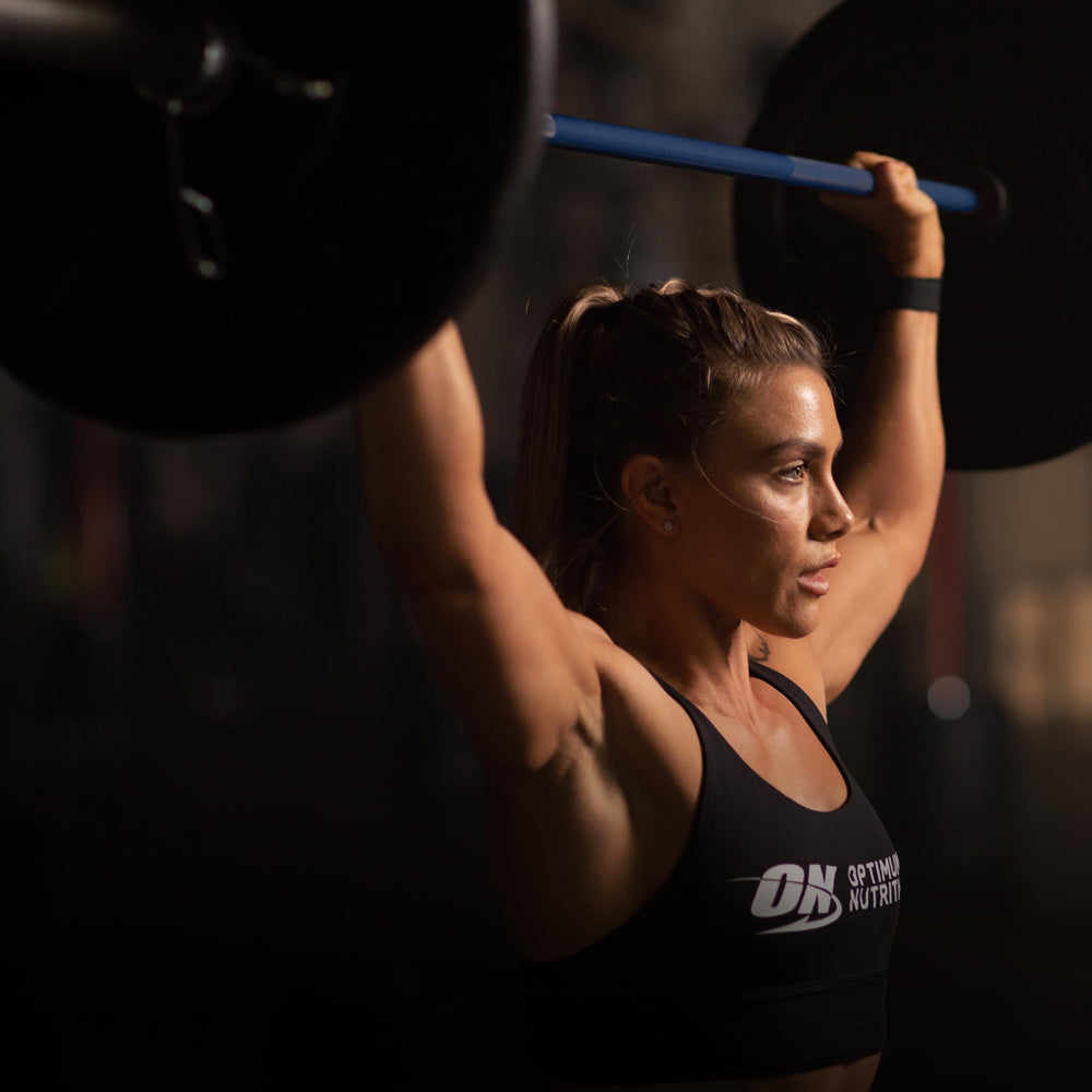 Optimum Nutrition en gimnasio junto a botella, práctico para llevar y mezclar