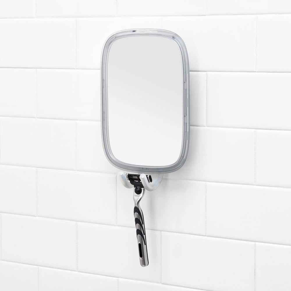 OXO espejo instalado en la ducha con una persona usándolo para el cuidado facial