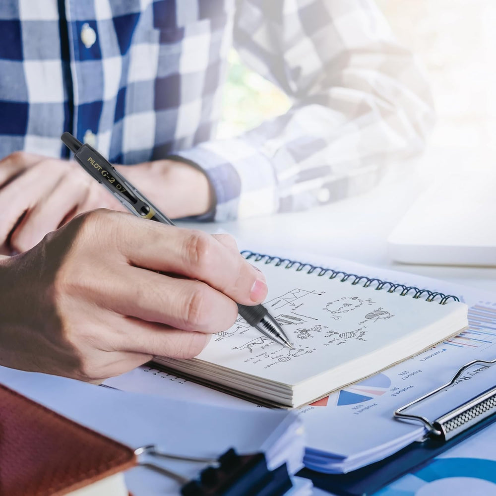 PILOT G2 escribiendo en un cuaderno, fluidez de tinta ideal para notas