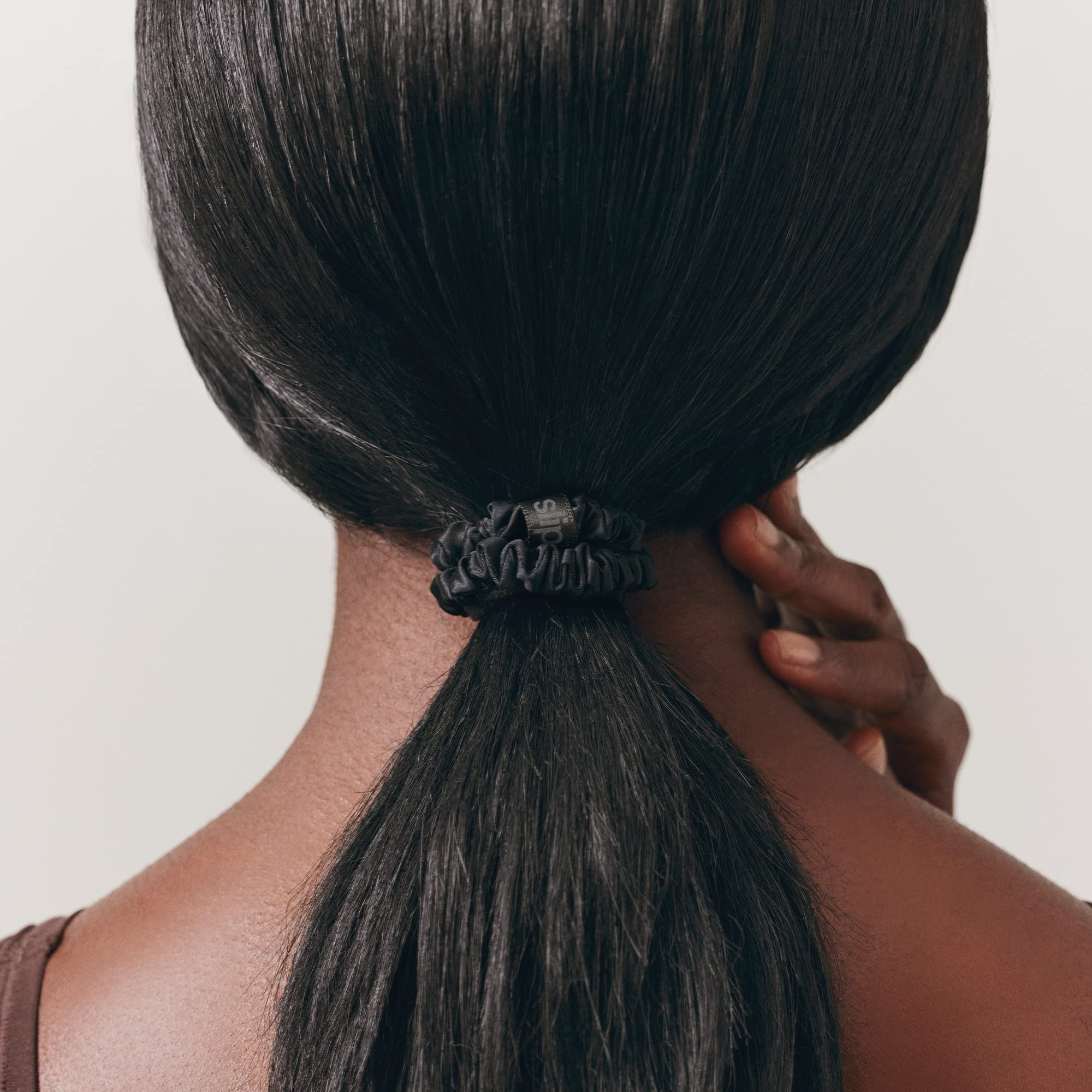 SLIP scrunchie junto a mano para comparar tamaño compacto y portabilidad