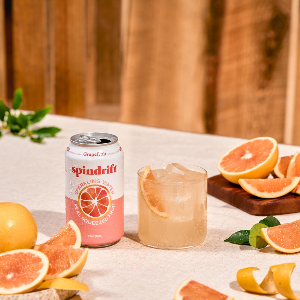 Pomelos frescos junto a una lata Spindrift resaltando jugo real