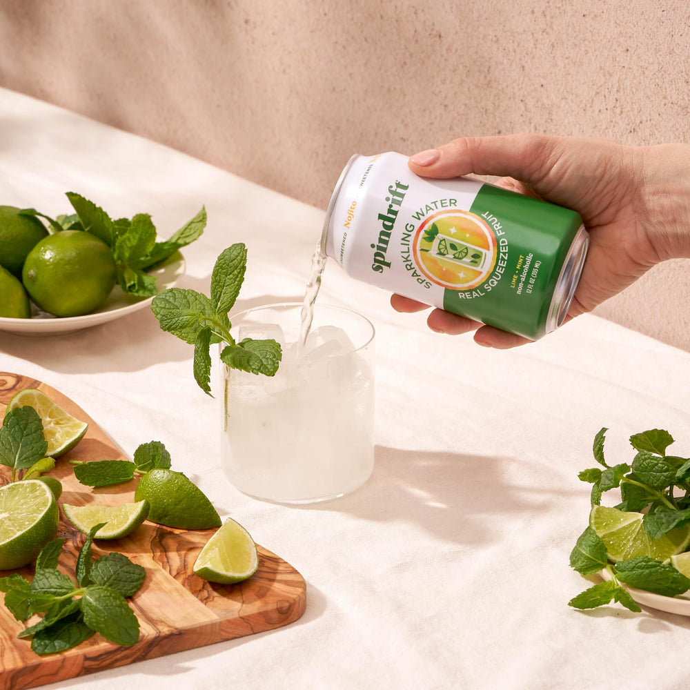 Comparación de tamaño de lata Spindrift Nojito con mano para escala