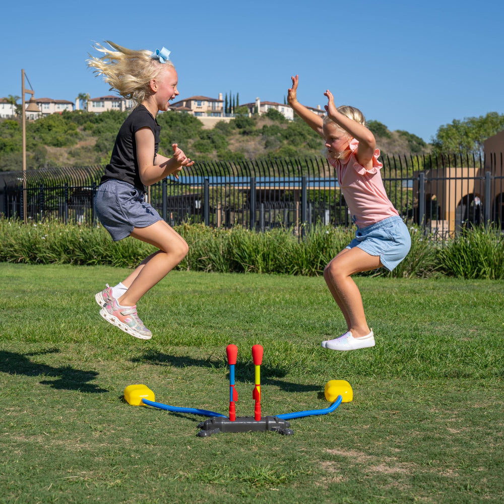 Group of kids using Stomp Rocket in backyard showing cooperative play and outdoor STEM learning