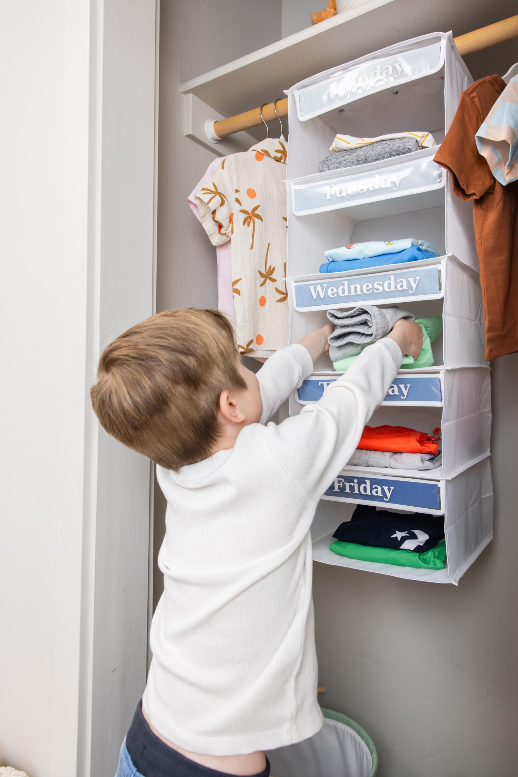 Three Sweet Peas Co child reaching into a shelf selecting clothes showing independence and faster mornings