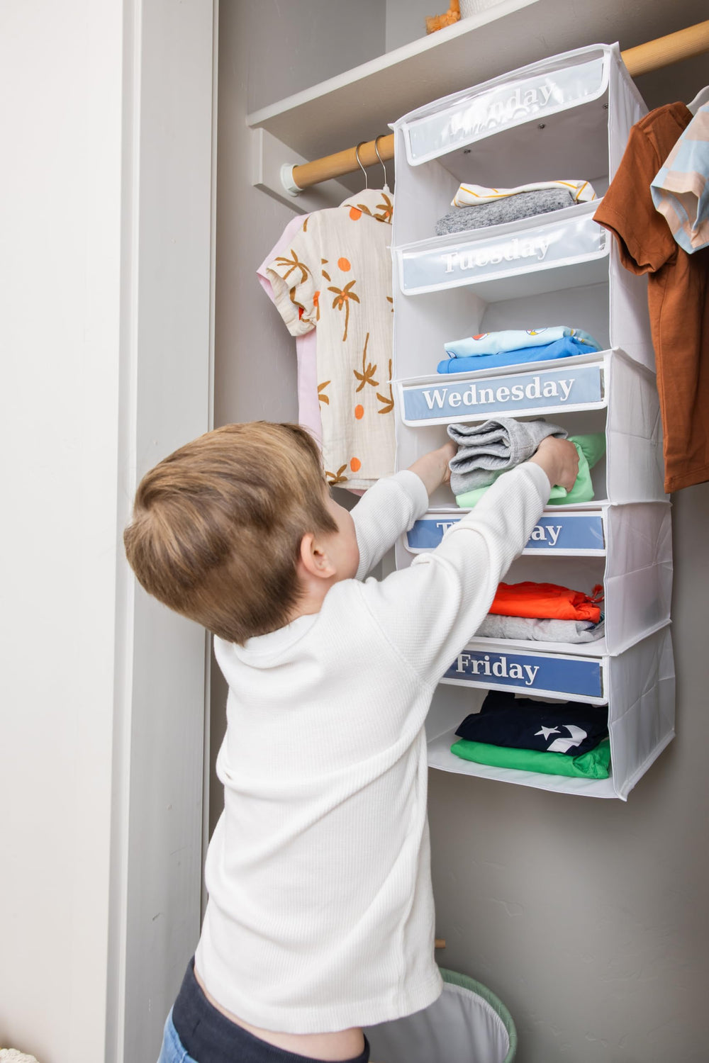 Three Sweet Peas Co child reaching into a shelf selecting clothes showing independence and faster mornings