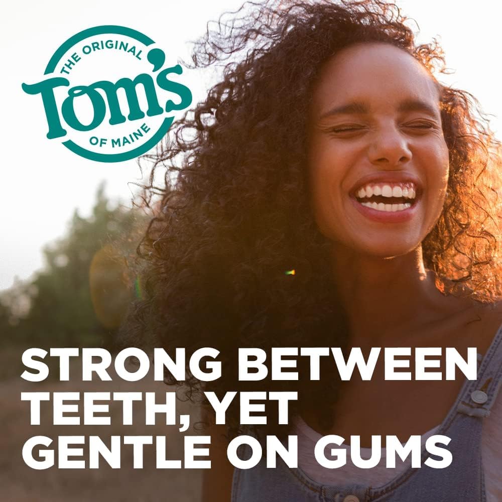 Manos usando el hilo Tom's of Maine entre dientes mostrando limpieza eficaz