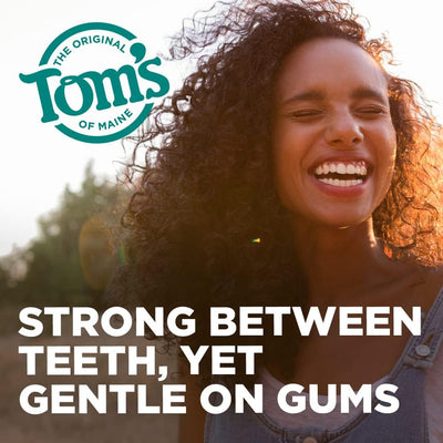 Manos usando el hilo Tom's of Maine entre dientes mostrando limpieza eficaz