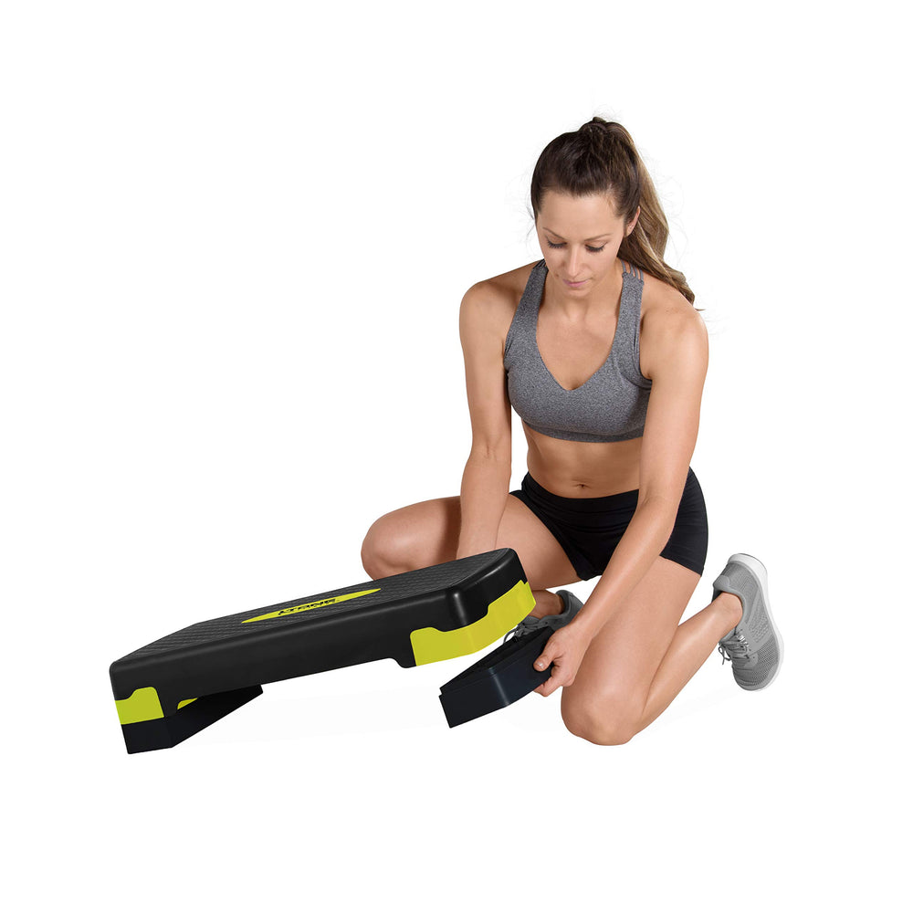 Tone Fitness step beside a person to show compact size and easy home storage