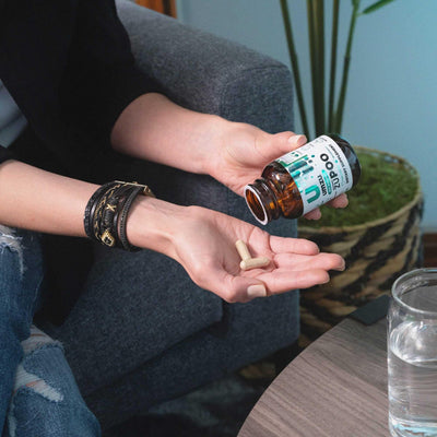 UMZU zuPOO capsule beside a glass of water illustrating recommended hydration during cleanse